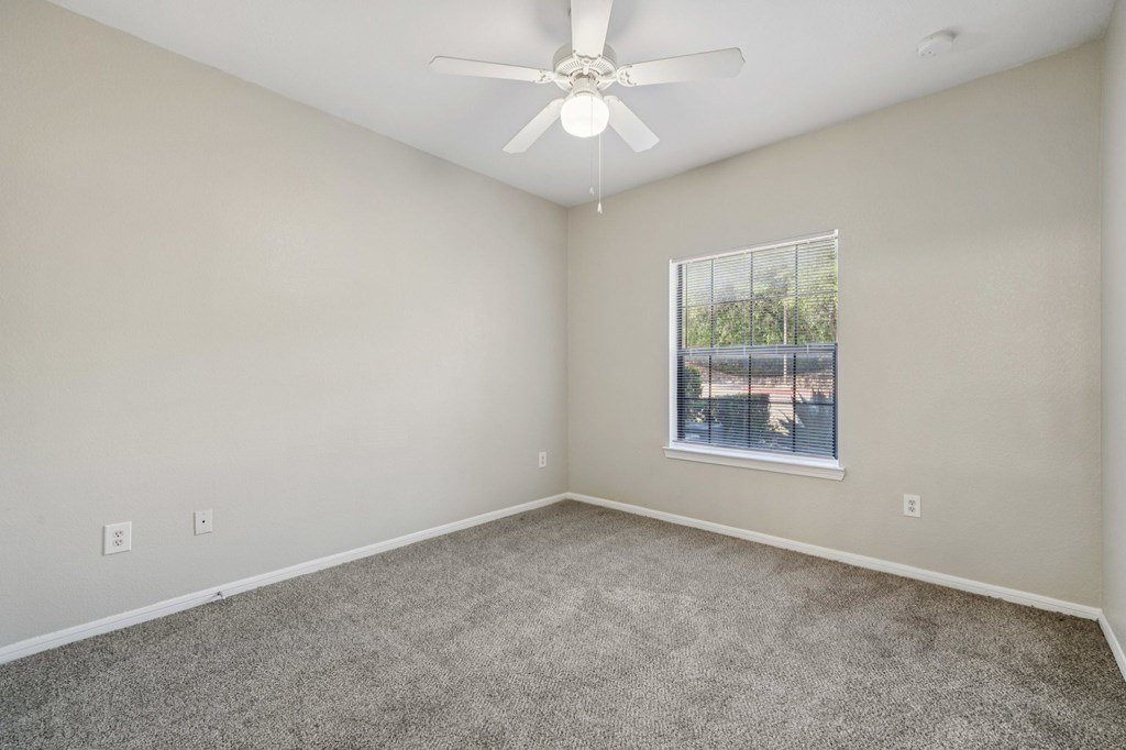 A room with a ceiling fan and a window.