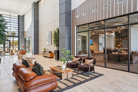 A modern living room with a brown leather sofa and a glass door leading to a balcony.
