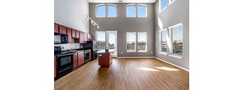 a kitchen and living room with windows and a wood floor