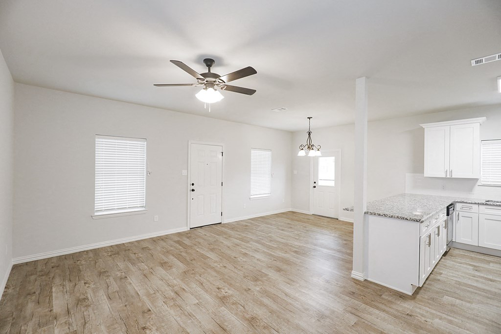 a kitchen and living room with hardwood floors and a ceiling fan