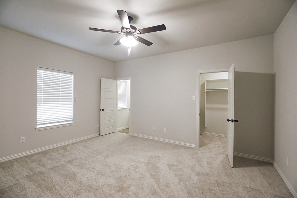 an empty bedroom with a ceiling fan