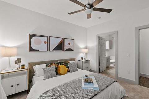 A bedroom with a bed, nightstand, and a ceiling fan.