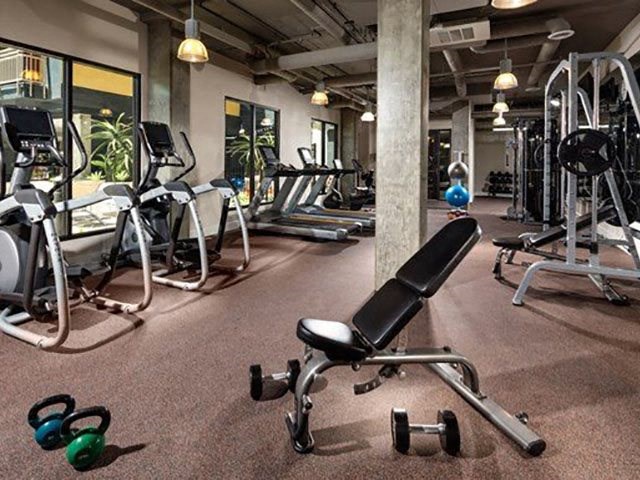 Two Bedroom Urban Apartments in Long Beach CA - Urban VIllage - Fitness Center with Dim Lighting, Machines, Equipment, and Large Windows