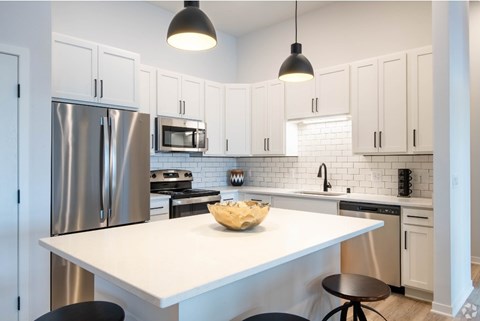 A modern kitchen with a white island and stainless steel appliances.