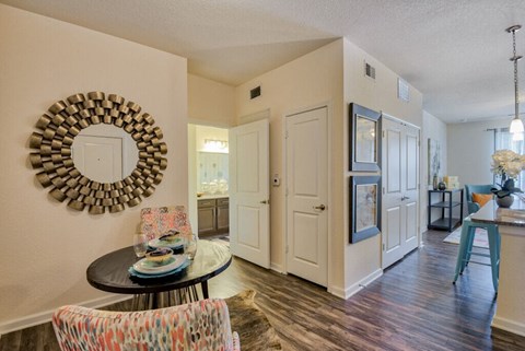 a living room and kitchen with a table and a mirror