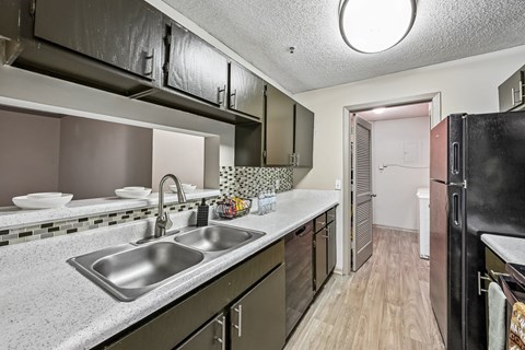A kitchen with a sink and a refrigerator.