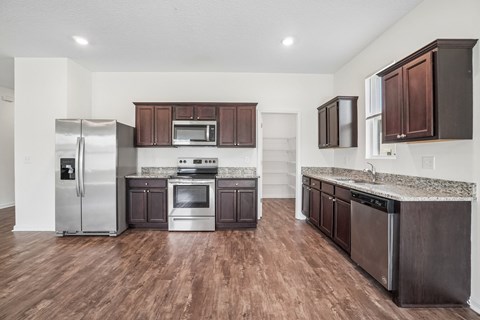 A kitchen with dark brown cabinets and a stainless steel refrigerator.