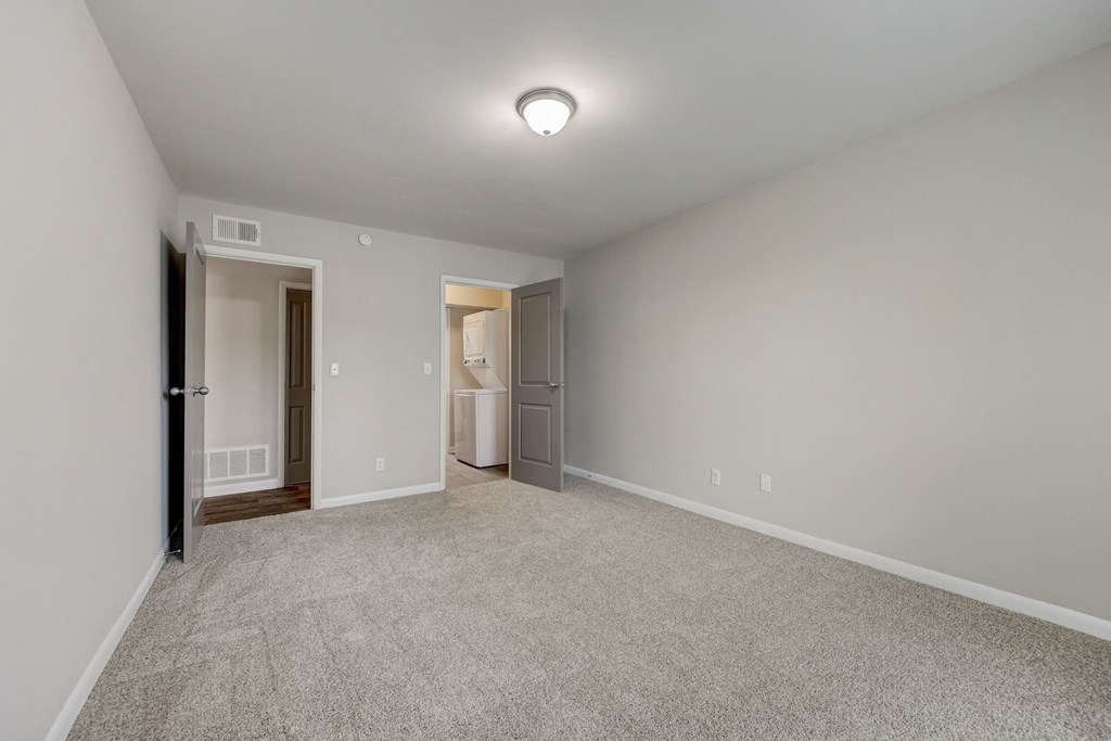 Sandy Springs, GA Apartments – Celebration at Sandy Springs -  a spacious living room with carpet and a door to a bathroom