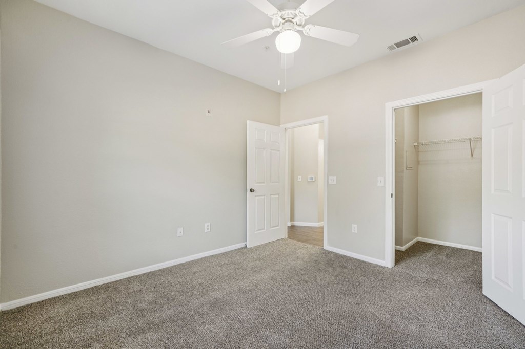 A room with a ceiling fan and carpeted floor.