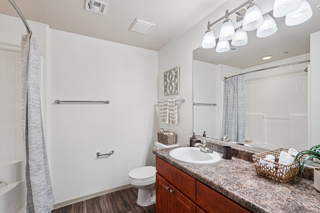 A bathroom with a toilet, sink, and mirror.