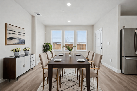 A dining room with a table set for six and a view of the outdoors through the windows.