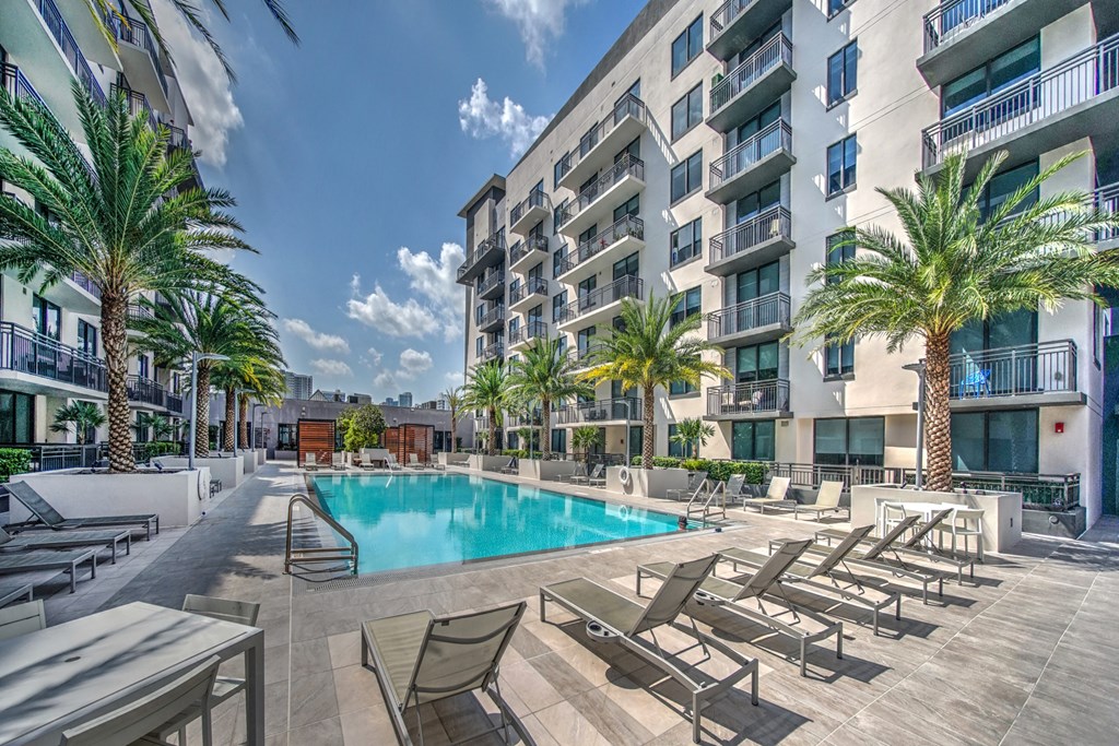 a pool with chairs and a building in the background