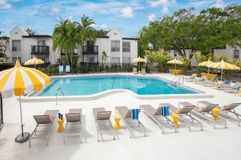 A pool surrounded by yellow umbrellas and lounge chairs.