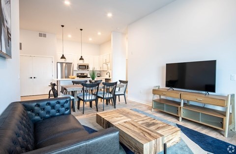 A modern living room with a black leather sofa and a wooden coffee table.