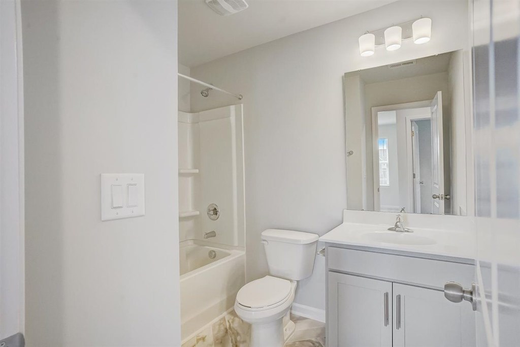 A white bathroom with a toilet, sink, and bathtub.