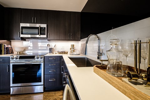 A modern kitchen with dark wood cabinets and stainless steel appliances.