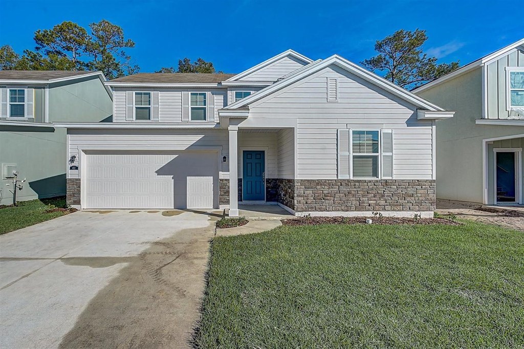 Two-story white house with a blue front door and stone accents.