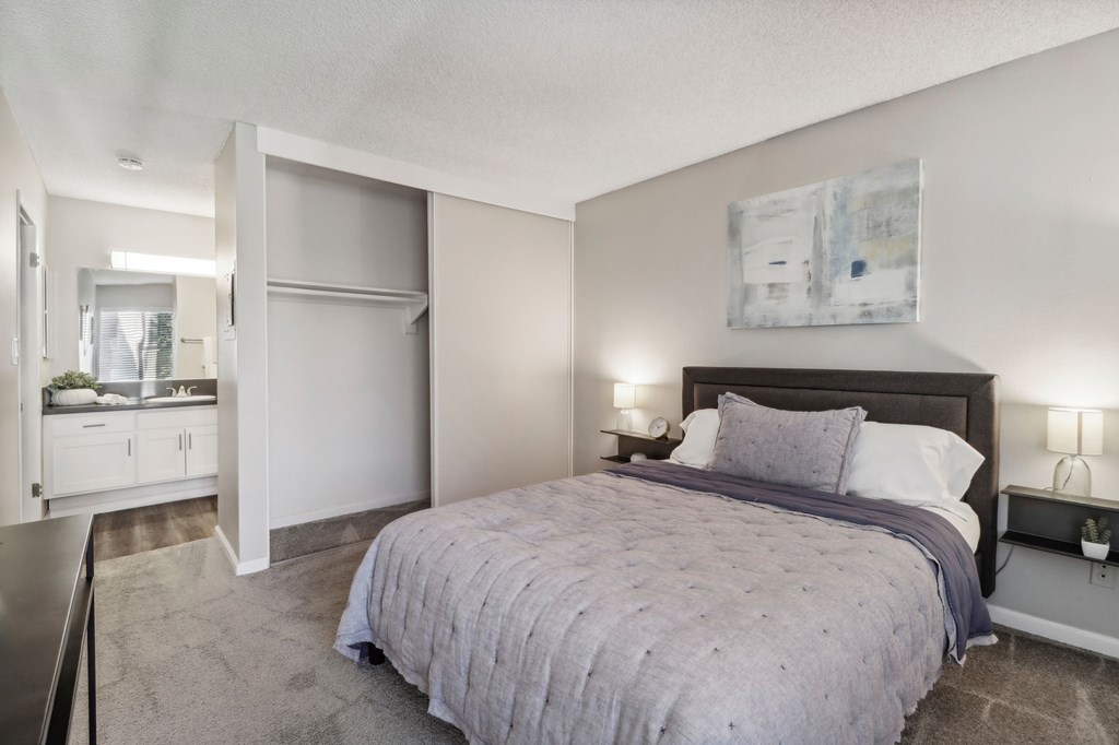 A bedroom with a bed, nightstand, and a painting on the wall.