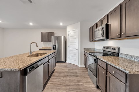 A kitchen with brown cabinets and a granite countertop.