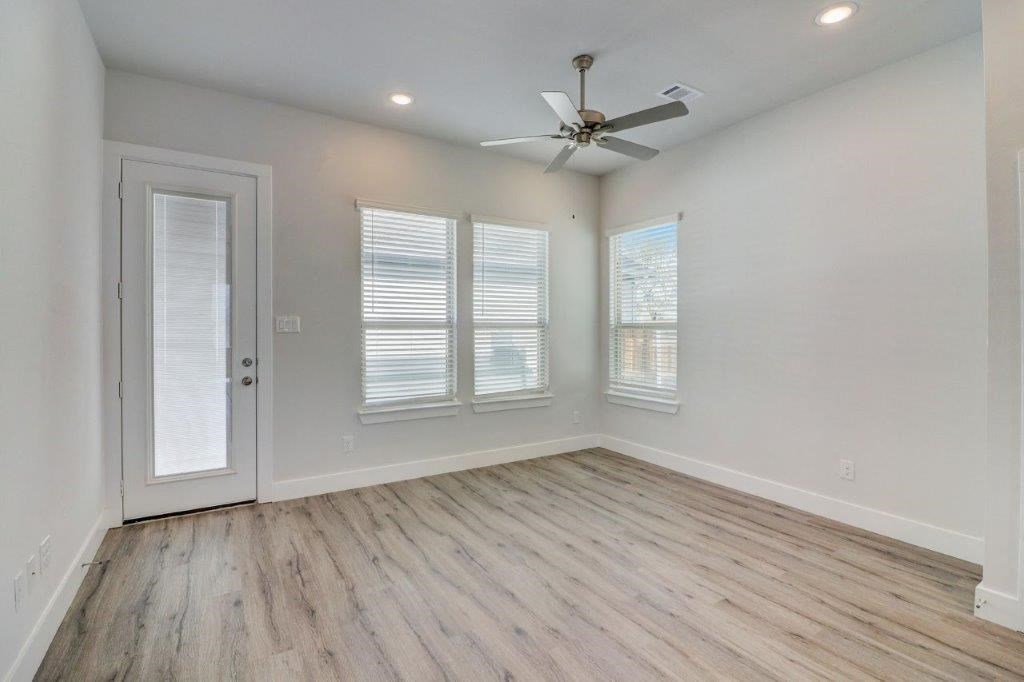 an empty living room with a ceiling fan and windows