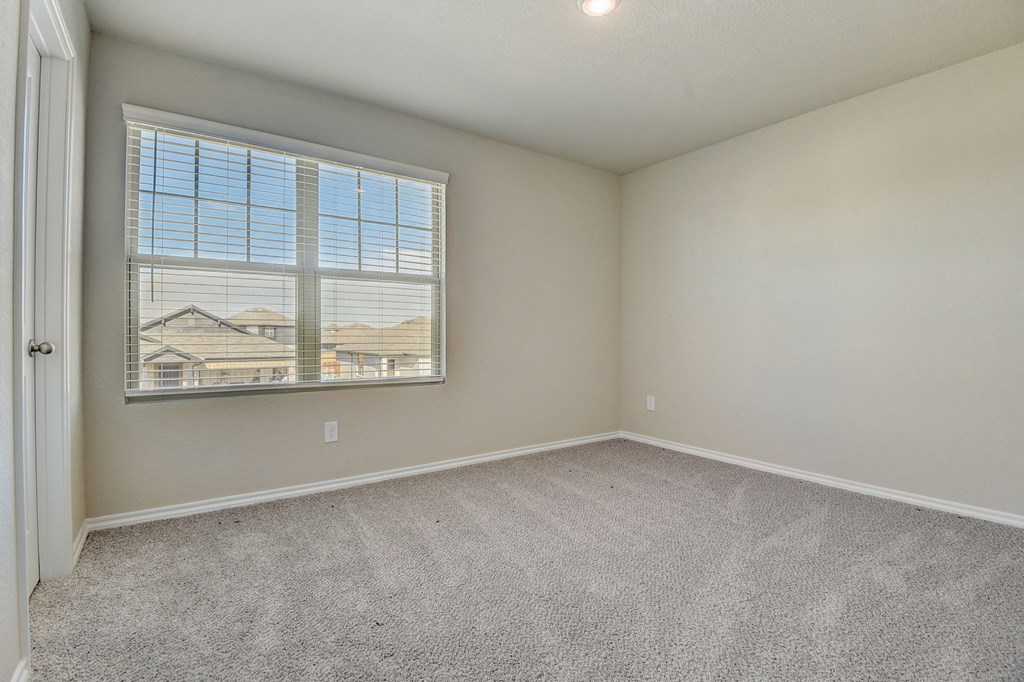 an empty bedroom with a large window and carpeting