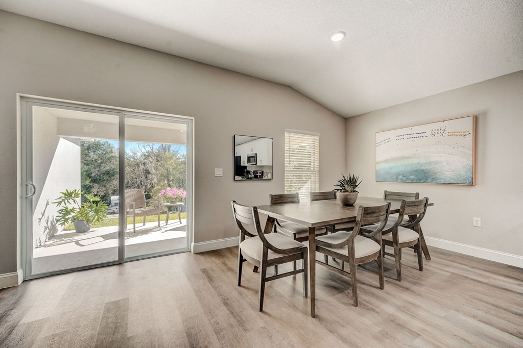 Dining room with patio doors, table, and chairs at The Groves at Lake Ella in Lady Lake, Florida, a pet-friendly rental community.
