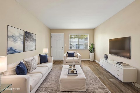 A living room with a white couch, a coffee table, and a television.