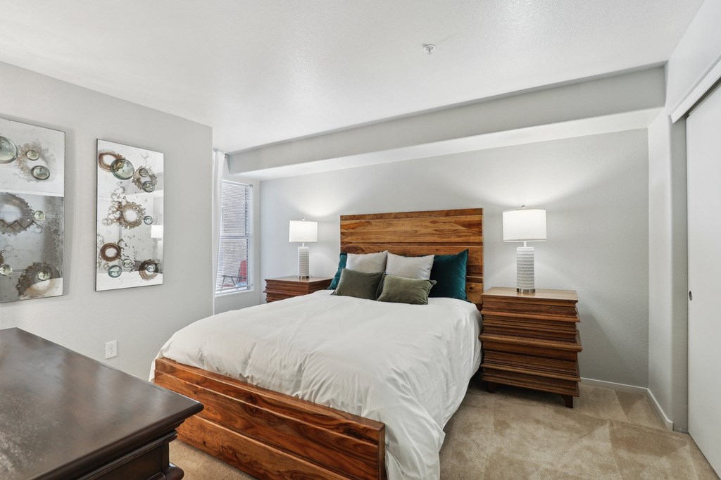 A bedroom with a bed, nightstand, and wall art.