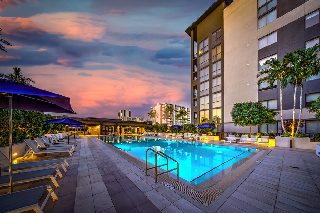 a swimming pool at a hotel with a sunset in the background