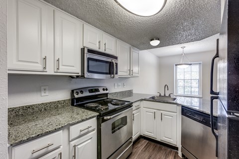 A kitchen with white cabinets and black appliances.
