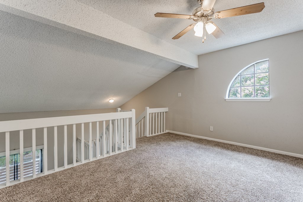 a large lofted bedroom with carpeted flooring and a ceiling fan