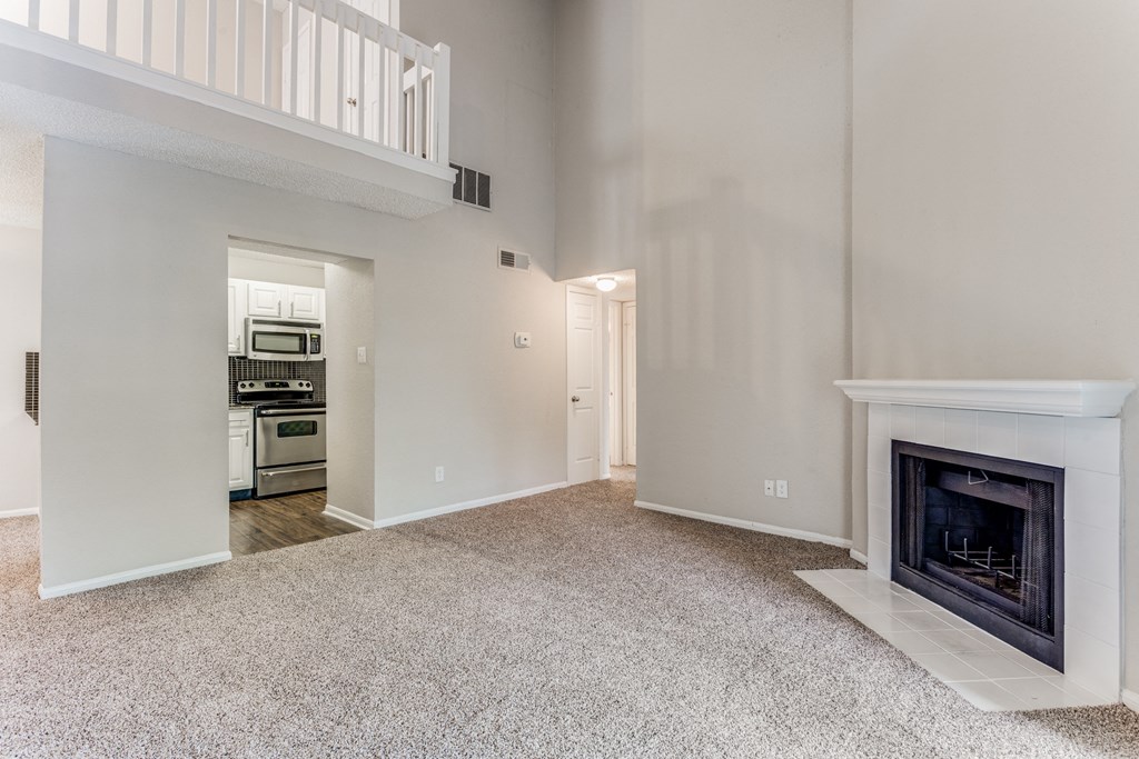 a living room with a fireplace and a kitchen in the background