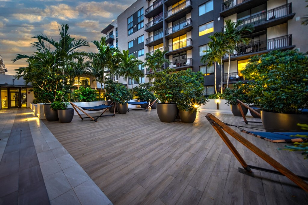 a large patio with potted plants and hammocks in an apartment building