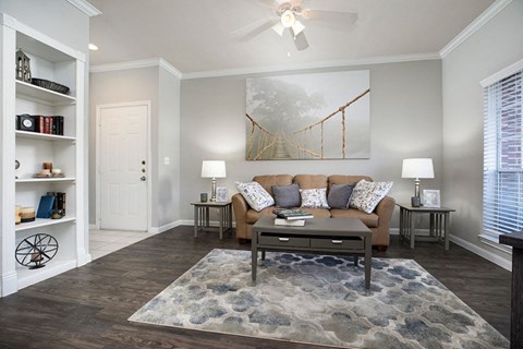 A living room with a couch, a rug, and a painting on the wall.