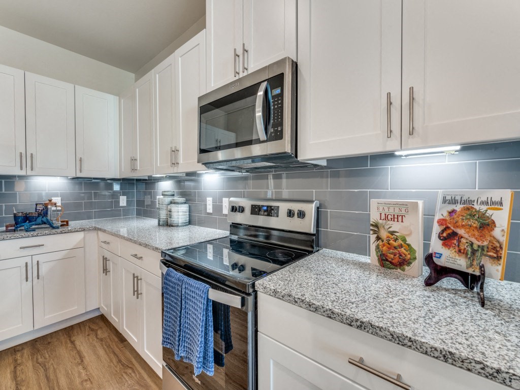 a kitchen with white cabinets and a stove and microwave