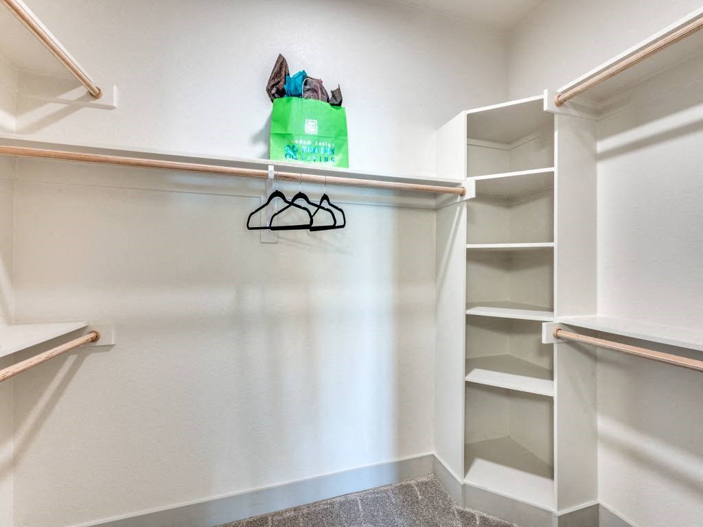 a walk in closet with shelves and a green bag