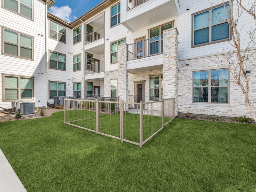 a fenced in yard in front of an apartment building