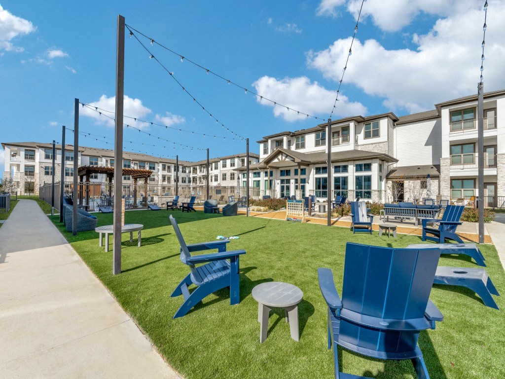 a grassy area with blue chairs and tables and buildings