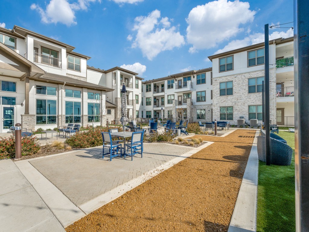 an outdoor patio with tables and chairs in front of an apartment building