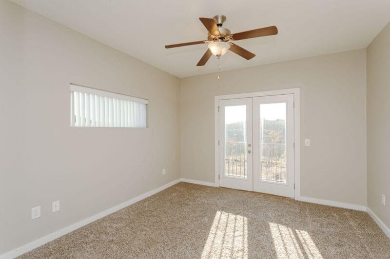 an empty living room with a ceiling fan and a window