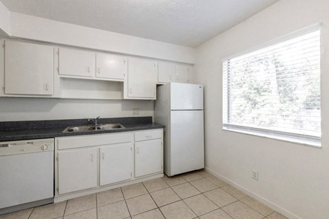 an empty kitchen with white appliances and a window