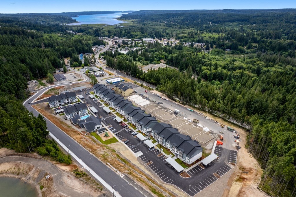 an aerial view of a building site with a parking lot and trees,