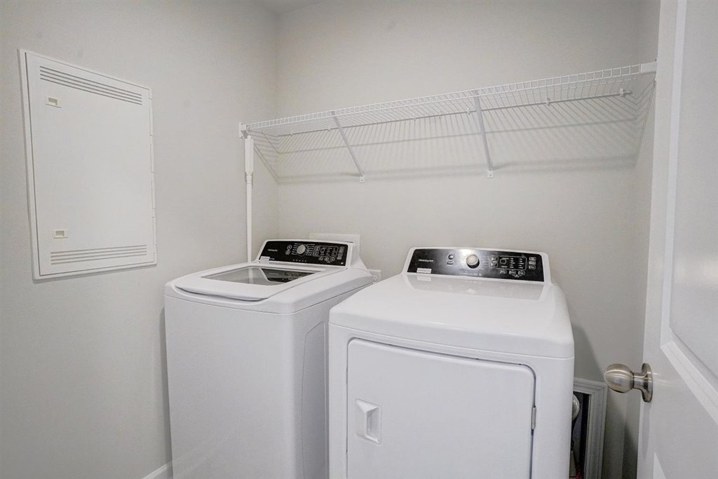 Two white front loading washing machines in a small laundry room.