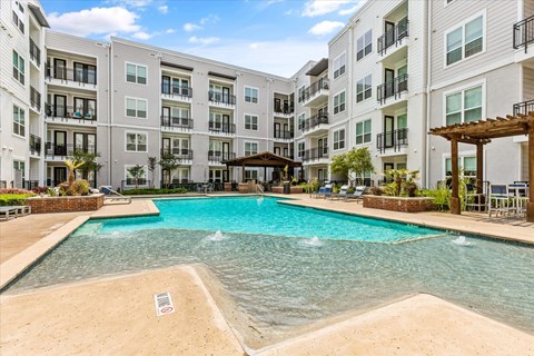 A large swimming pool in front of apartment buildings.