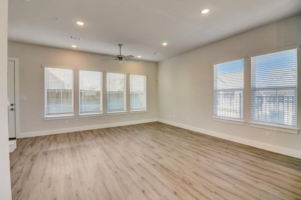 an empty living room with wood floors and a ceiling fan