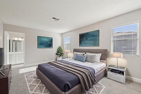 A bedroom with a large bed and two paintings on the wall.