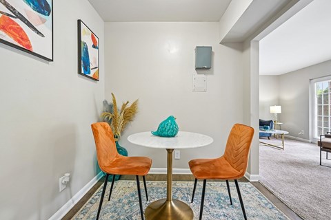 A dining room with a white table and orange chairs.
