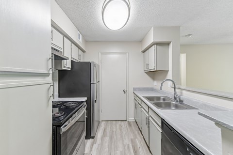 A kitchen with a black fridge and stove top oven.