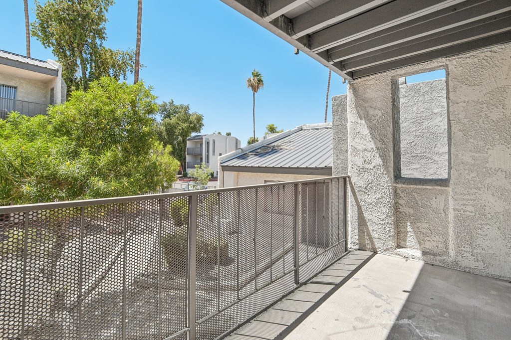 A balcony with a metal railing and a concrete wall.