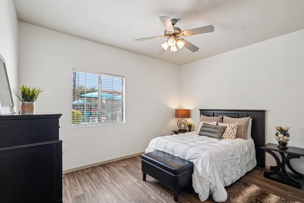 A bedroom with a bed, nightstand, and a window with blinds.
